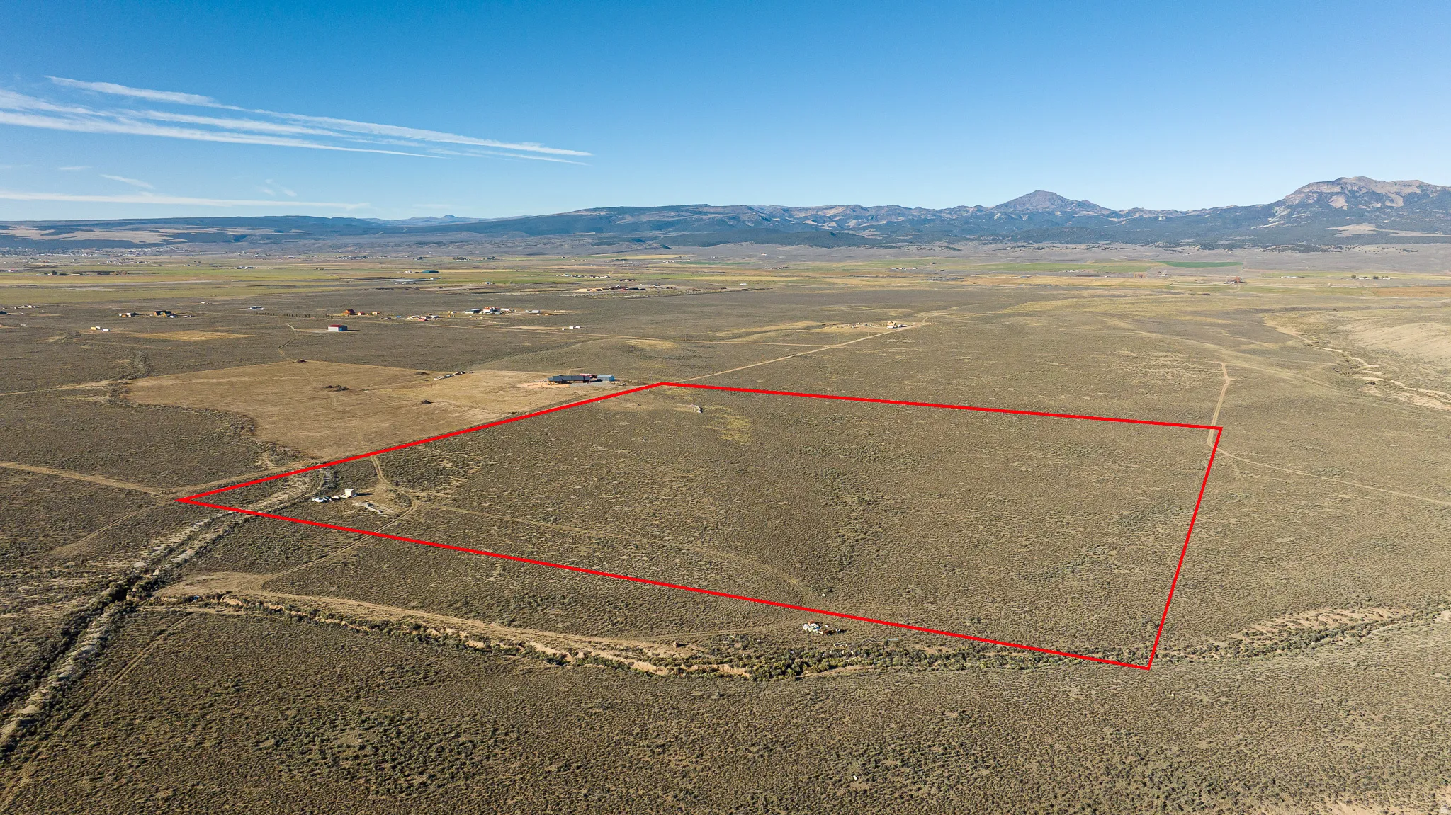 Aerial view of sparsely populated area with property boundaries highlighted and a mountainous background