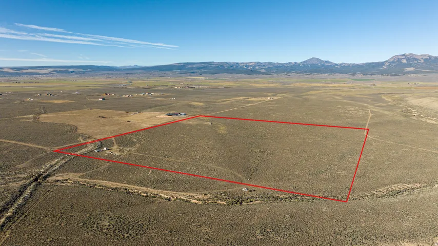 Aerial view of sparsely populated area with property boundaries highlighted and a mountainous background