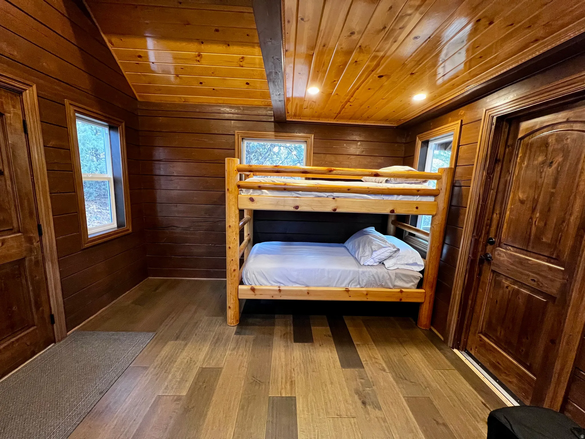 Bedroom featuring wood-type flooring, wood walls, wooden ceiling, and lofted ceiling