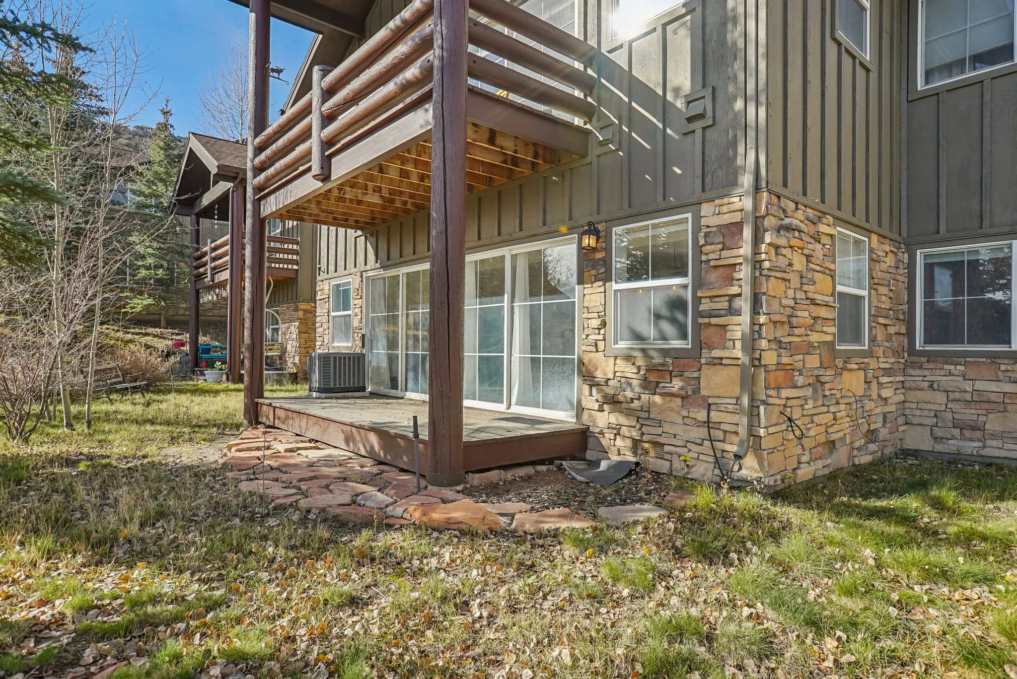 View of home's exterior featuring board and batten siding, stone siding, a deck, and a balcony