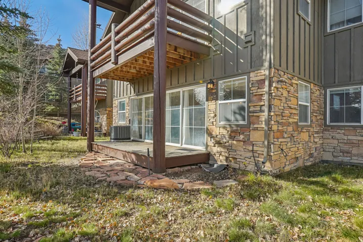 View of home's exterior featuring board and batten siding, stone siding, a deck, and a balcony