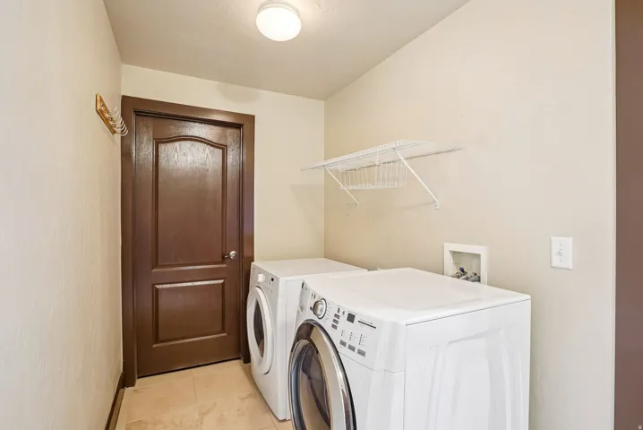 Laundry area with light tile patterned flooring and washing machine and clothes dryer