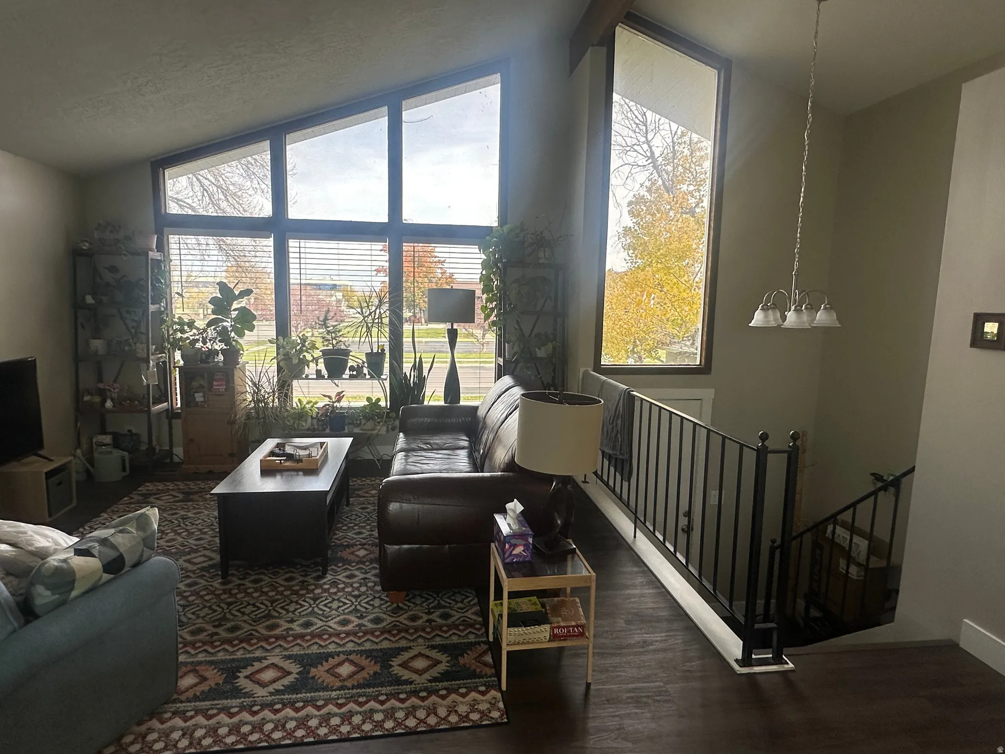 Living area featuring lofted ceiling, dark wood-type flooring, healthy amount of natural light, a chandelier, and a textured ceiling