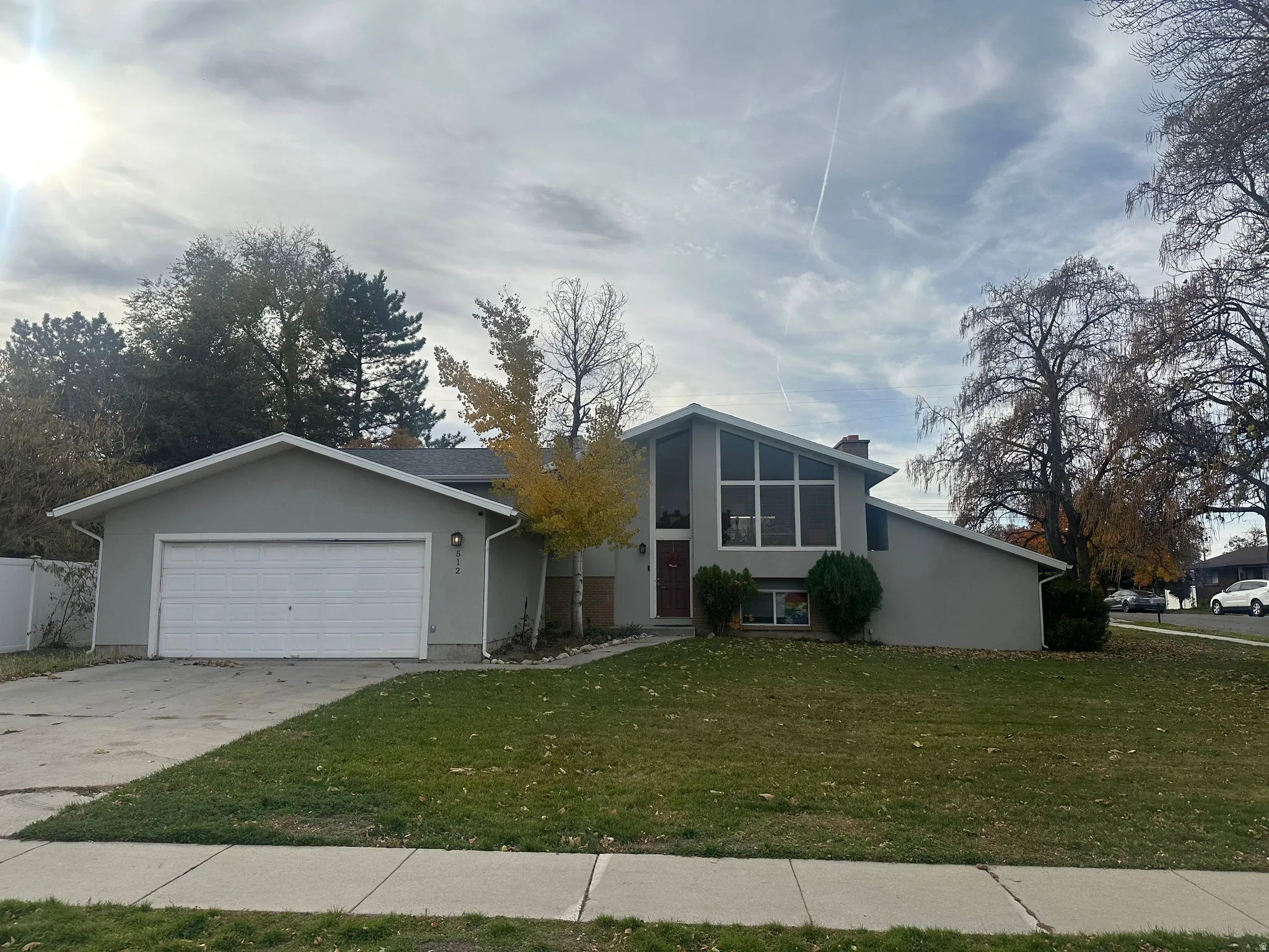 Mid-century inspired home with a front yard, stucco siding, driveway, and an attached garage