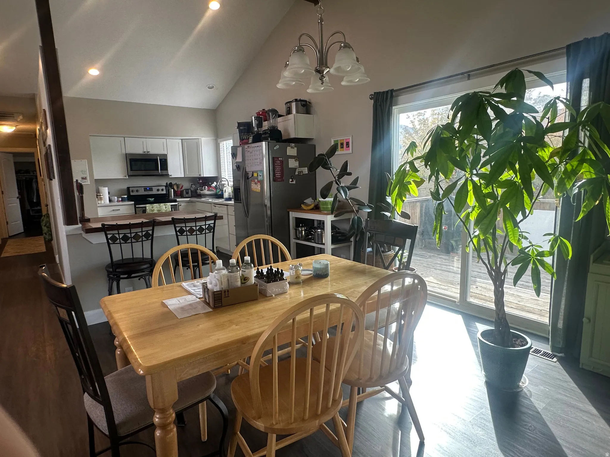 Dining space featuring wood finished floors, a chandelier, high vaulted ceiling, and recessed lighting