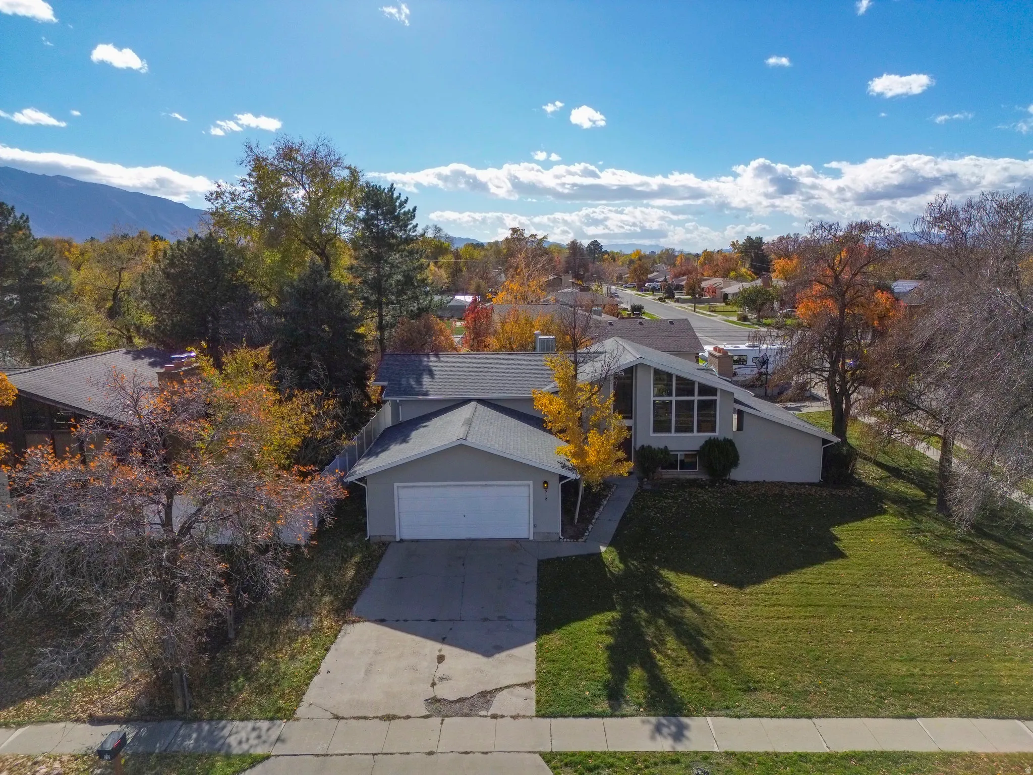 View of front facade featuring a front yard, driveway, a garage, and stucco siding