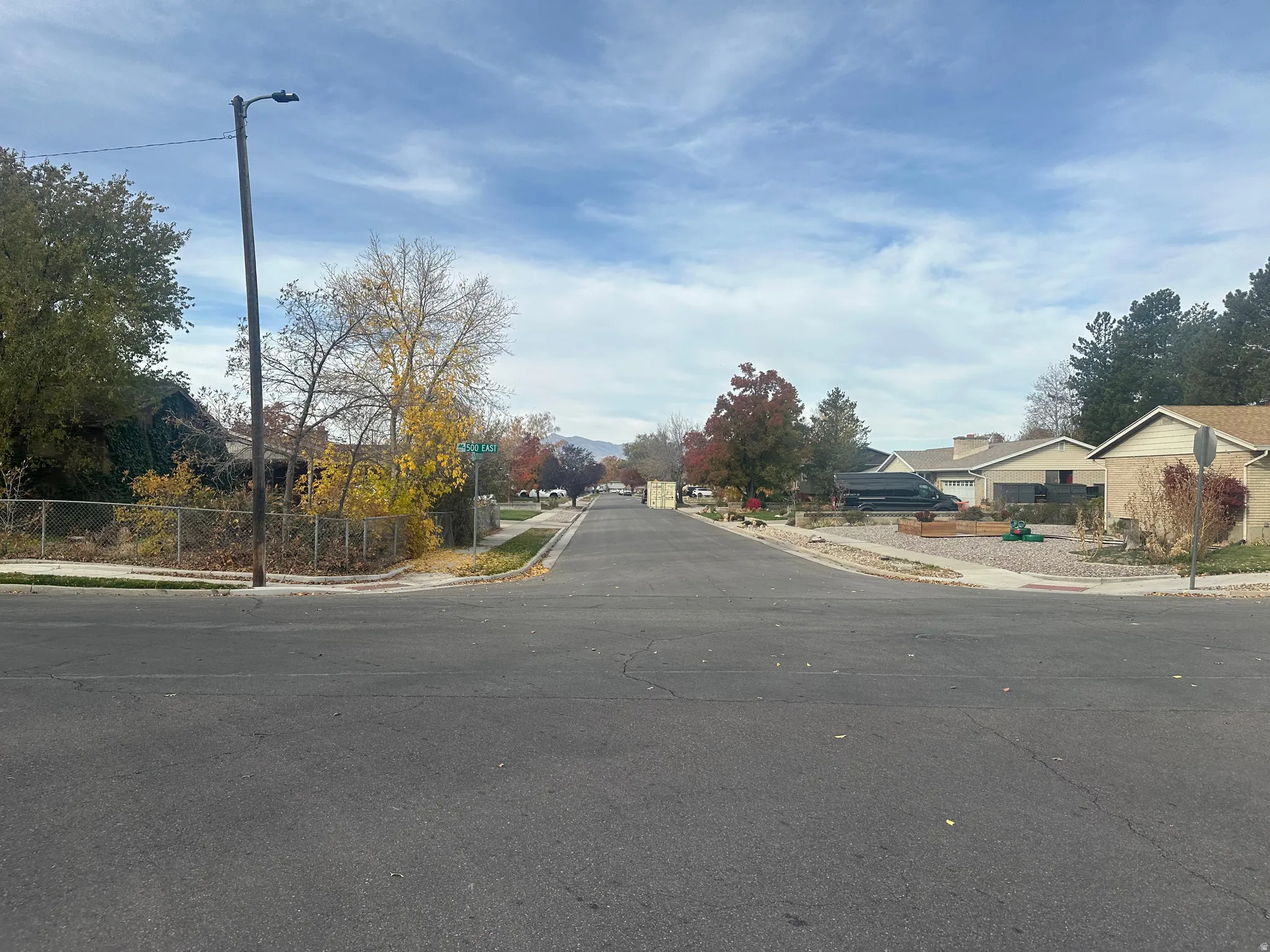 View of asphalt street featuring sidewalks, curbs, traffic signs, and a residential view