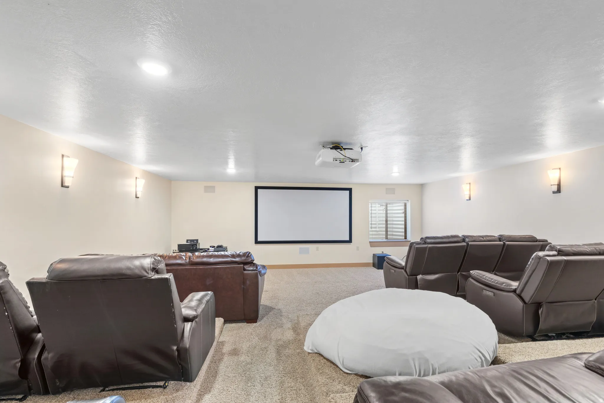 Carpeted home theater room with a textured ceiling and baseboards