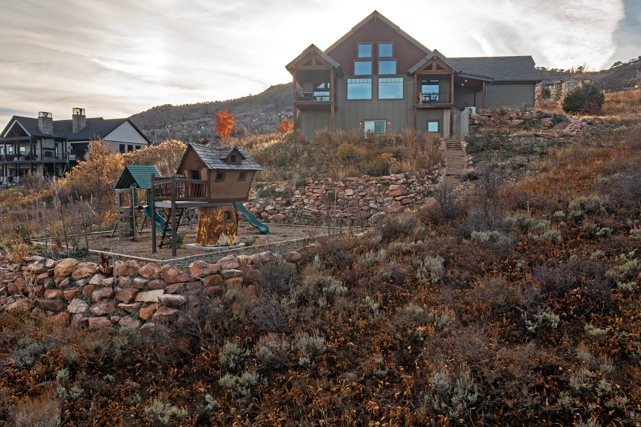 Back of house featuring a playground, a patio, a balcony, and a mountain view