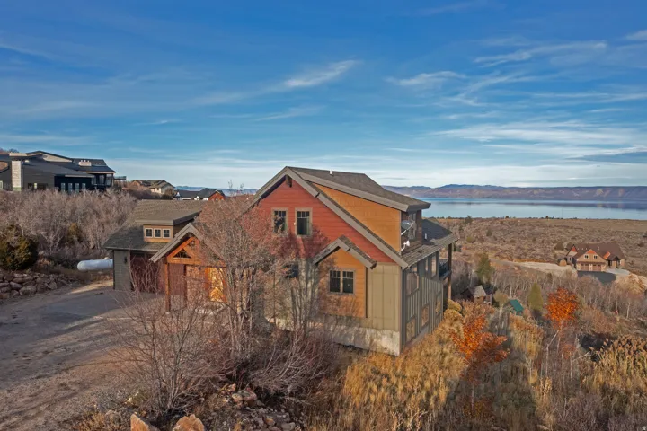 View of side of property featuring a shingled roof and a water view