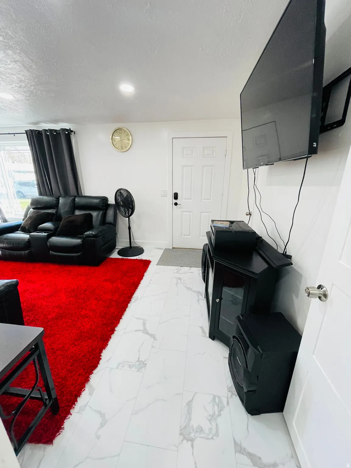 Living area with a textured ceiling and light marble finish floors