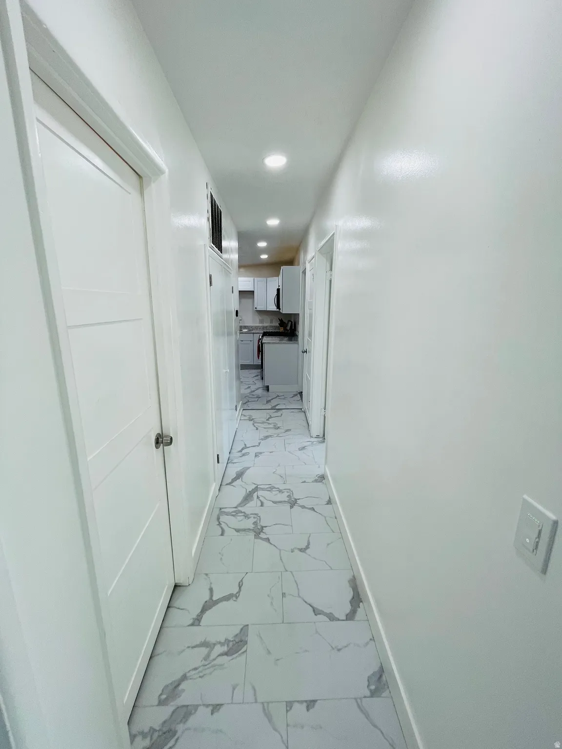 Corridor with light marble finish floors and recessed lighting