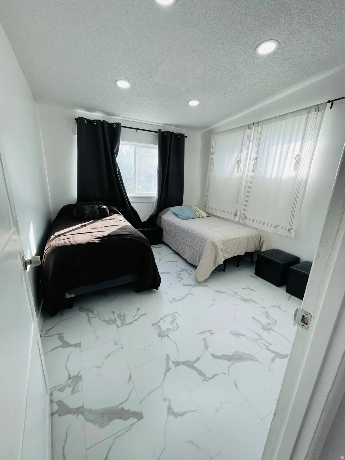 Bedroom with marble look tile flooring, a textured ceiling, and recessed lighting