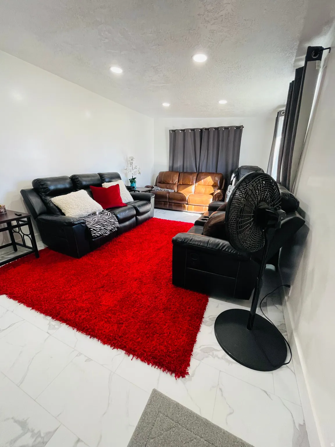 Living area with a textured ceiling, light marble finish flooring, and recessed lighting