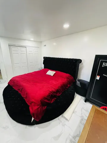 Bedroom with light marble finish floors, recessed lighting, and a closet