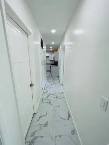 Corridor with light marble finish floors and recessed lighting