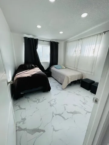Bedroom with marble look tile flooring, a textured ceiling, and recessed lighting