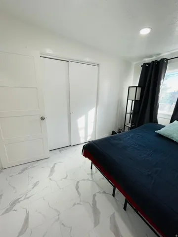 Bedroom featuring light marble finish floors and a closet