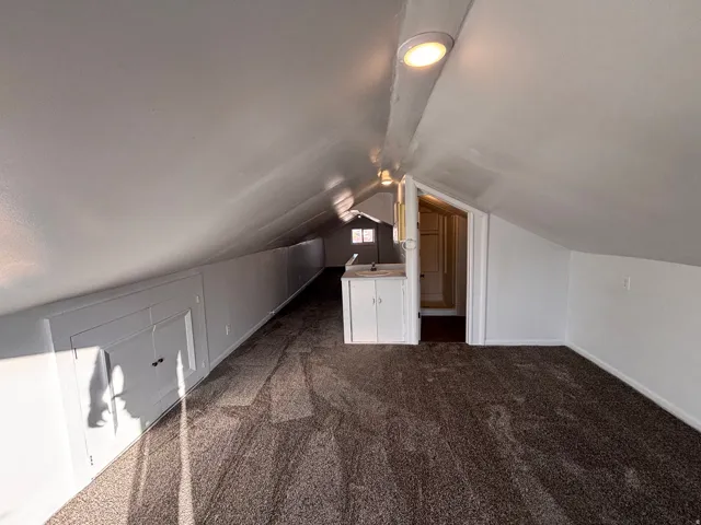 Bonus room featuring dark colored carpet and vaulted ceiling