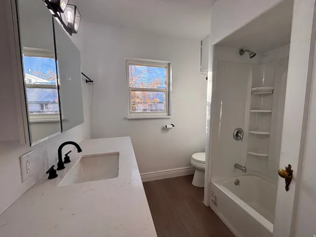 Full bath with vanity, shower / tub combo with curtain, and dark wood finished floors