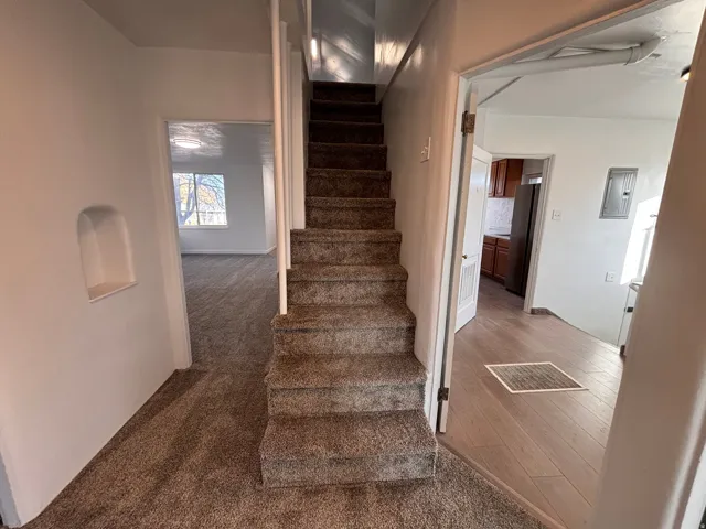 Stairs featuring electric panel and carpet