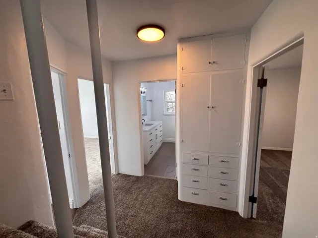 Corridor featuring dark colored carpet