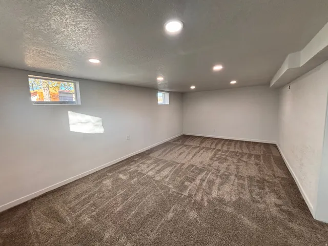 Below grade area with dark colored carpet, recessed lighting, and a textured ceiling