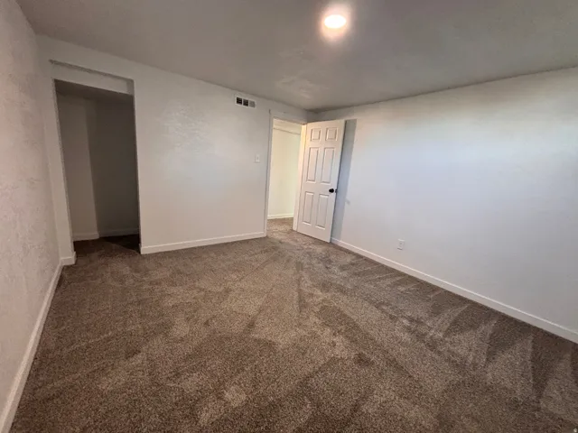 Spare room with dark colored carpet and baseboards