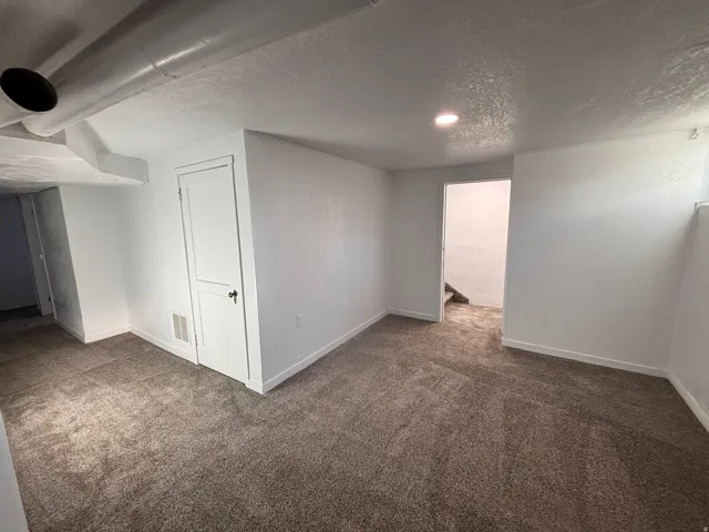 Basement with a textured ceiling and dark carpet