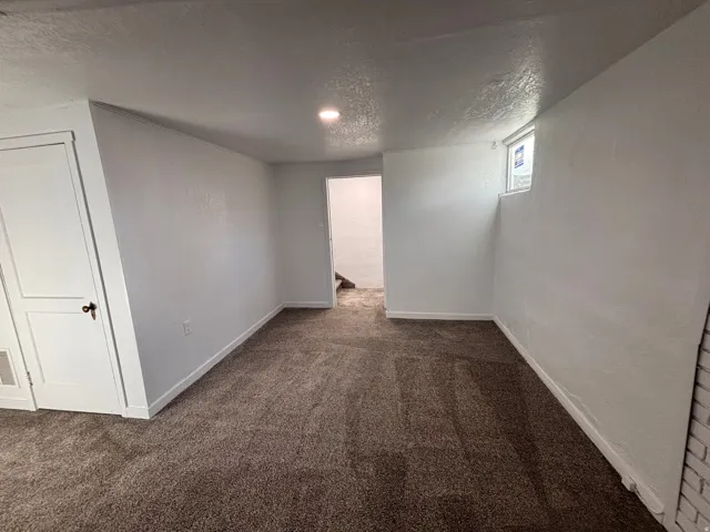 Unfurnished room featuring dark colored carpet and a textured ceiling