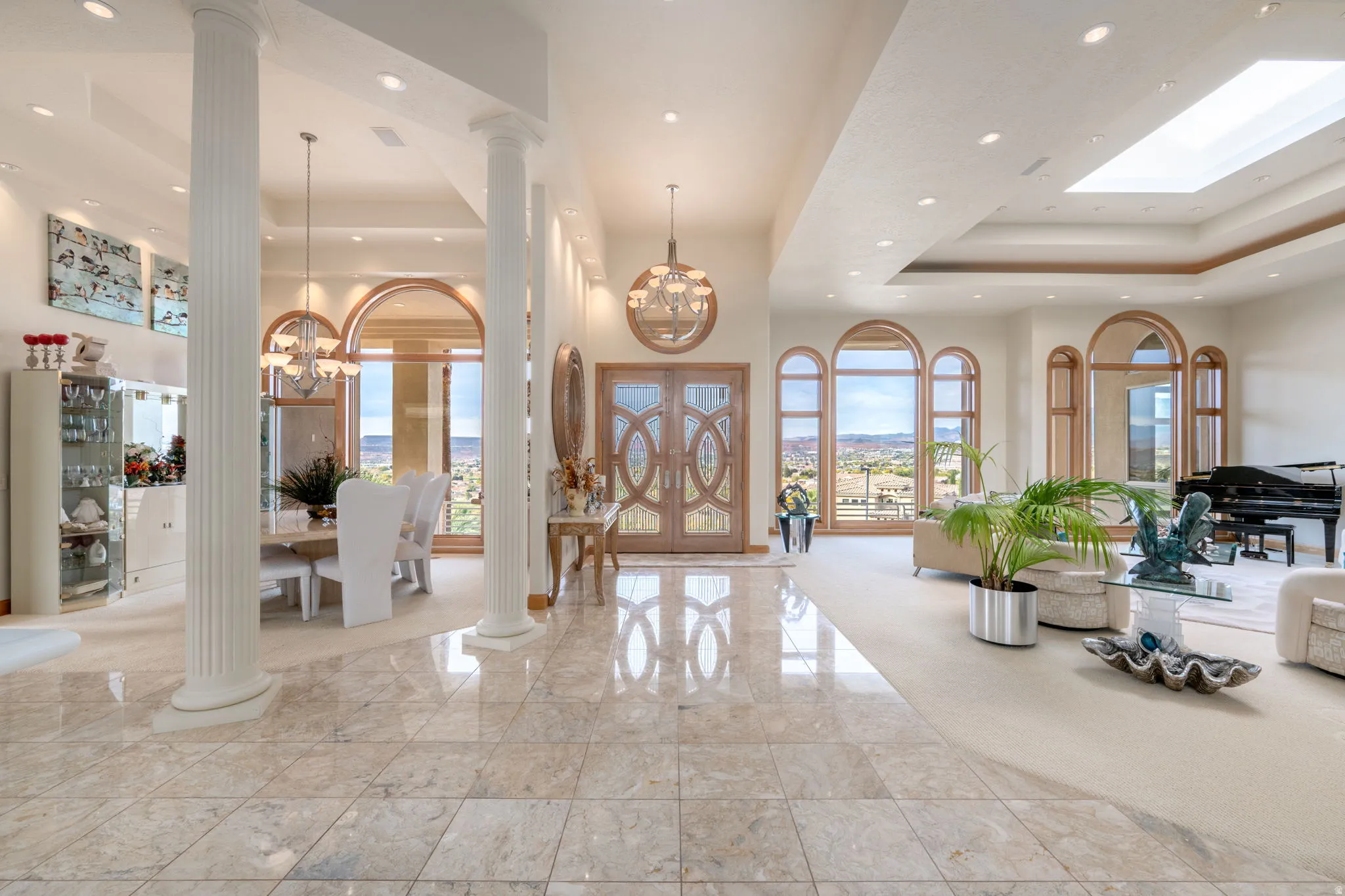 Entrance foyer featuring a tray ceiling, a chandelier, recessed lighting, ornate columns, and a high ceiling