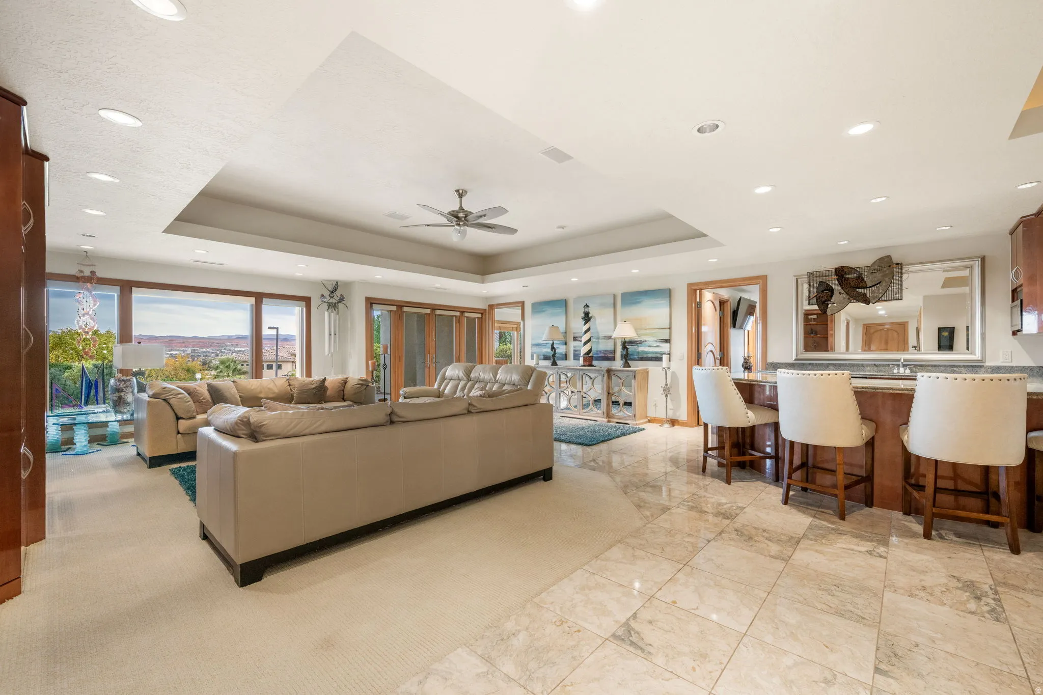 Living area featuring a raised ceiling, a ceiling fan, and recessed lighting