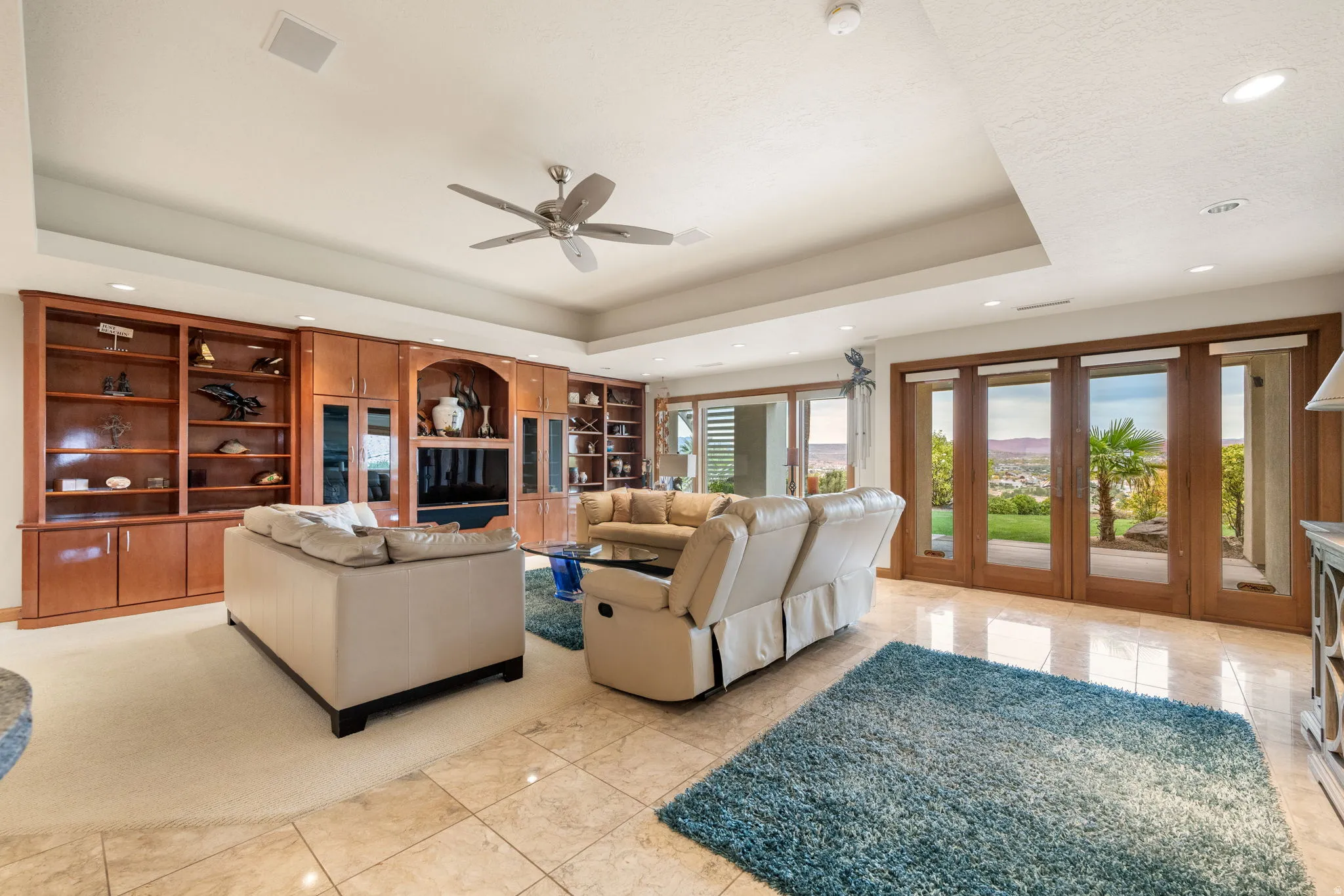 Living area featuring a raised ceiling, recessed lighting, ceiling fan, and light tile patterned flooring