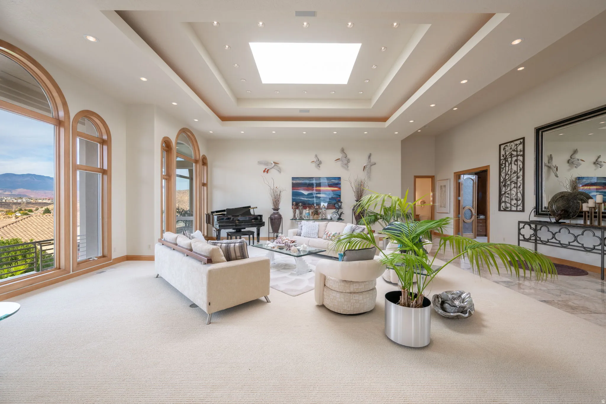Living room with a tray ceiling, a skylight, a high ceiling, carpet floors, and a mountain view