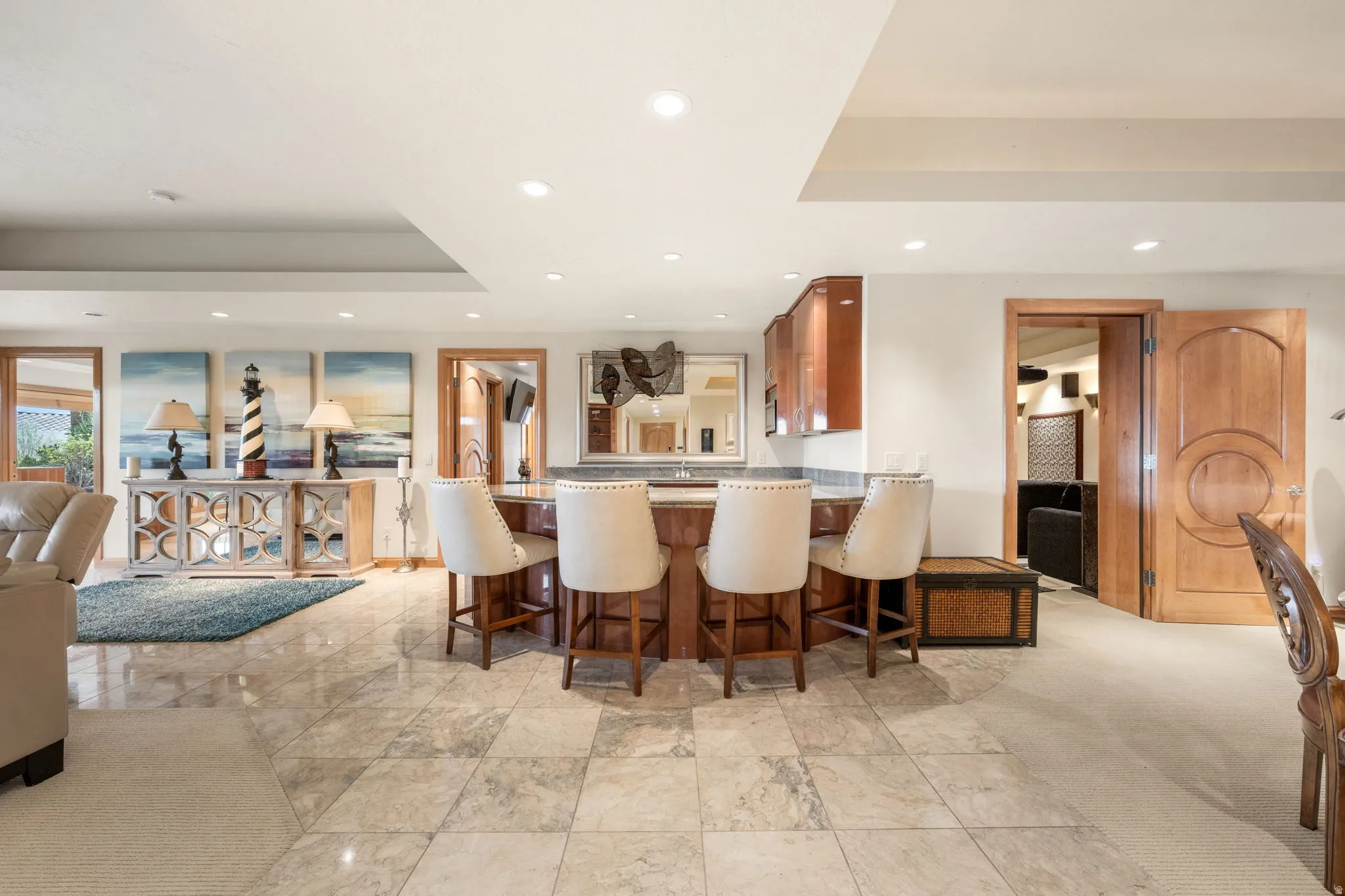 Kitchen featuring a raised ceiling, brown cabinetry, recessed lighting, a kitchen breakfast bar, and a peninsula
