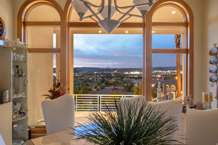Expansive arched windows frame a distant cityscape, desert mountains, and a golf course