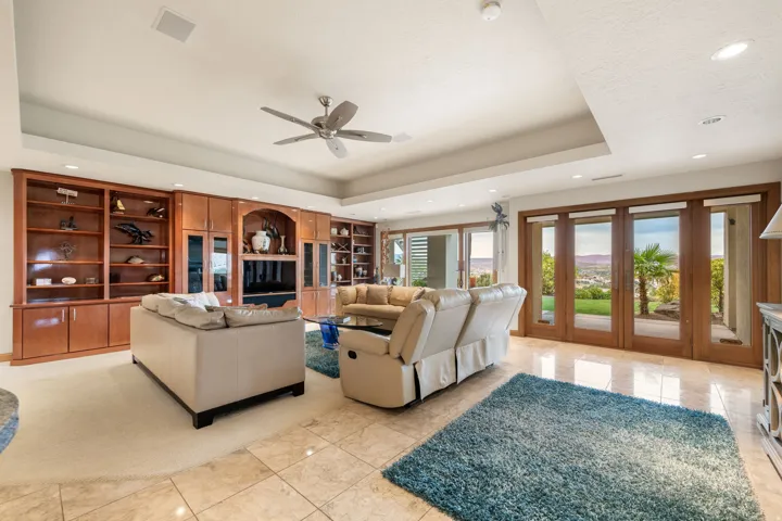 Living area featuring a raised ceiling, recessed lighting, ceiling fan, and light tile patterned flooring