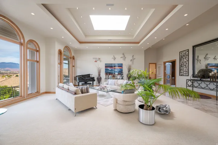Living room with a tray ceiling, a skylight, a high ceiling, carpet floors, and a mountain view