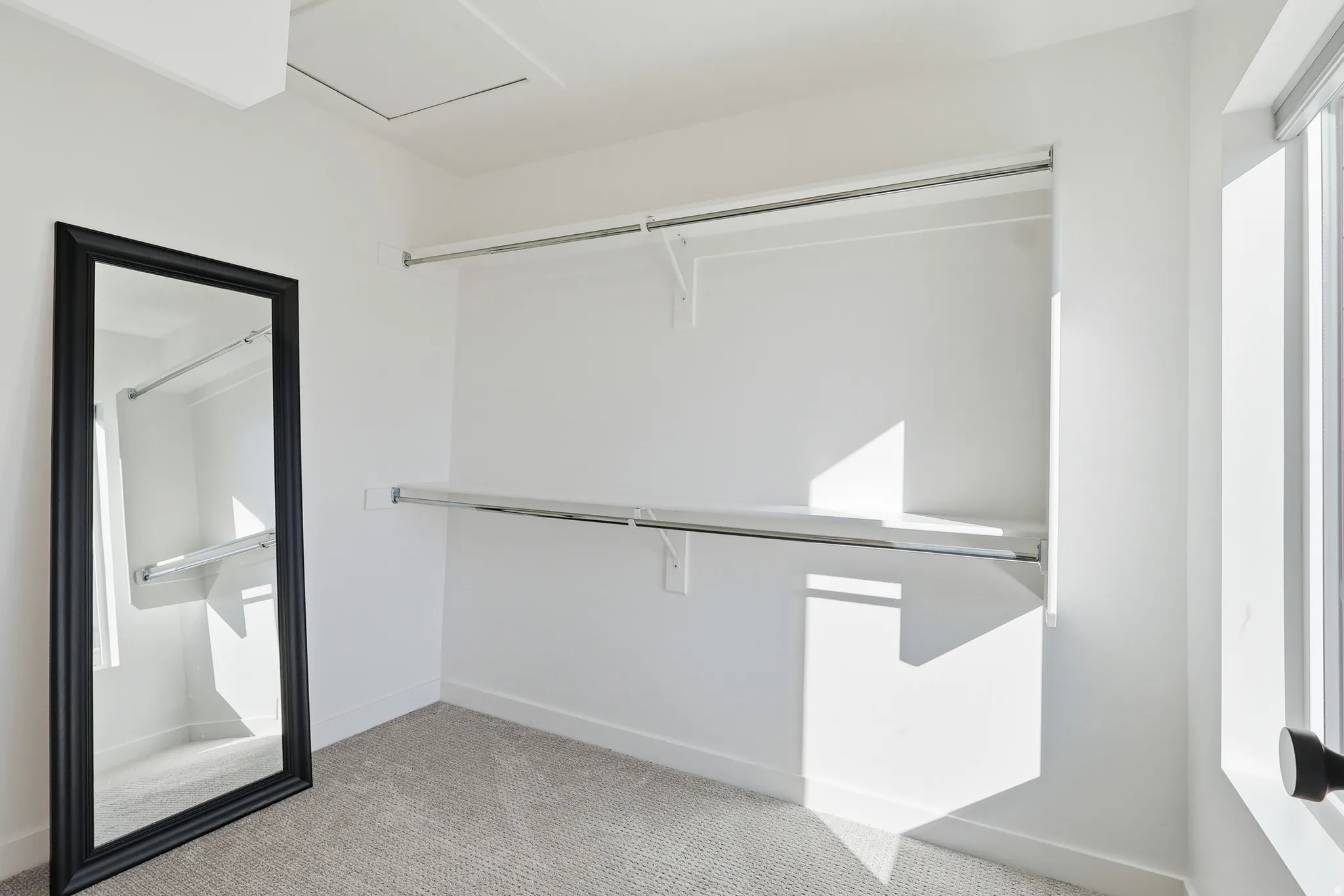 Walk in closet with light carpet and attic access