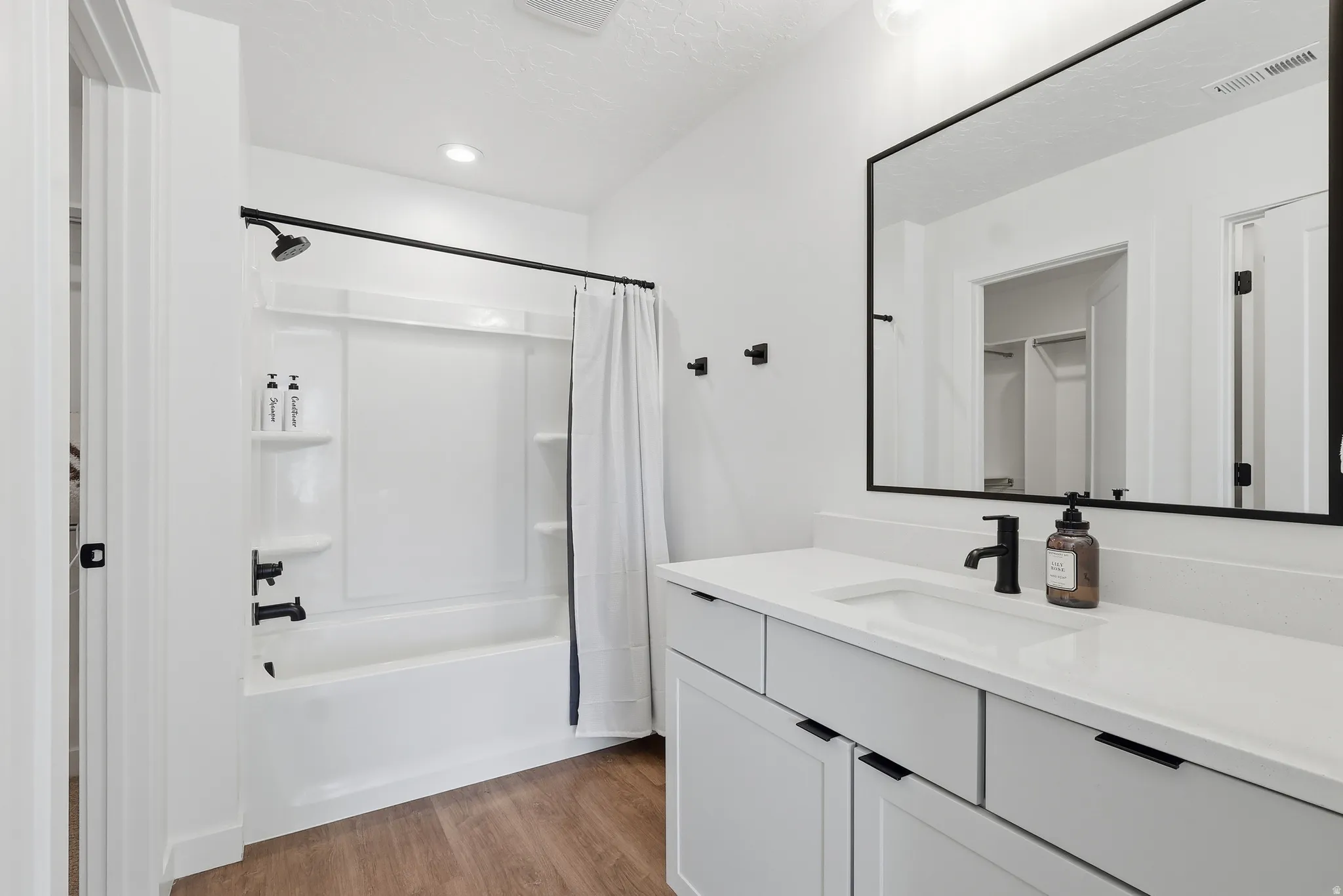 Bathroom featuring shower / bathtub combination with curtain, vanity, light wood-type flooring, a textured ceiling, and recessed lighting