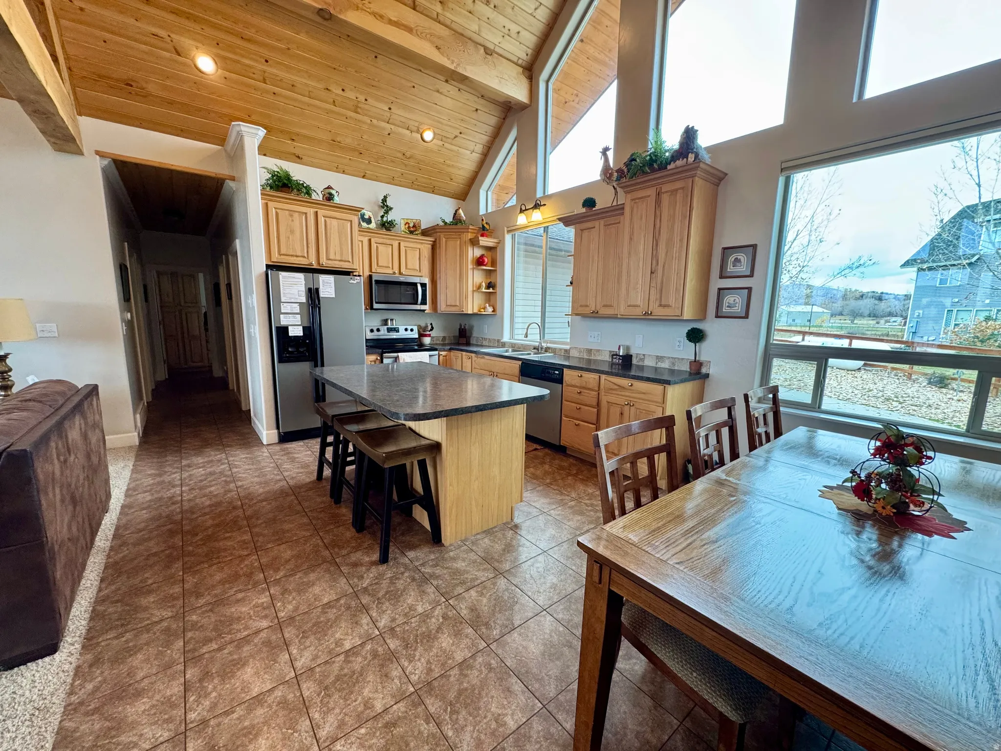 Kitchen with open shelves, a kitchen island, high vaulted ceiling, appliances with stainless steel finishes, and a wood ceiling with exposed beams