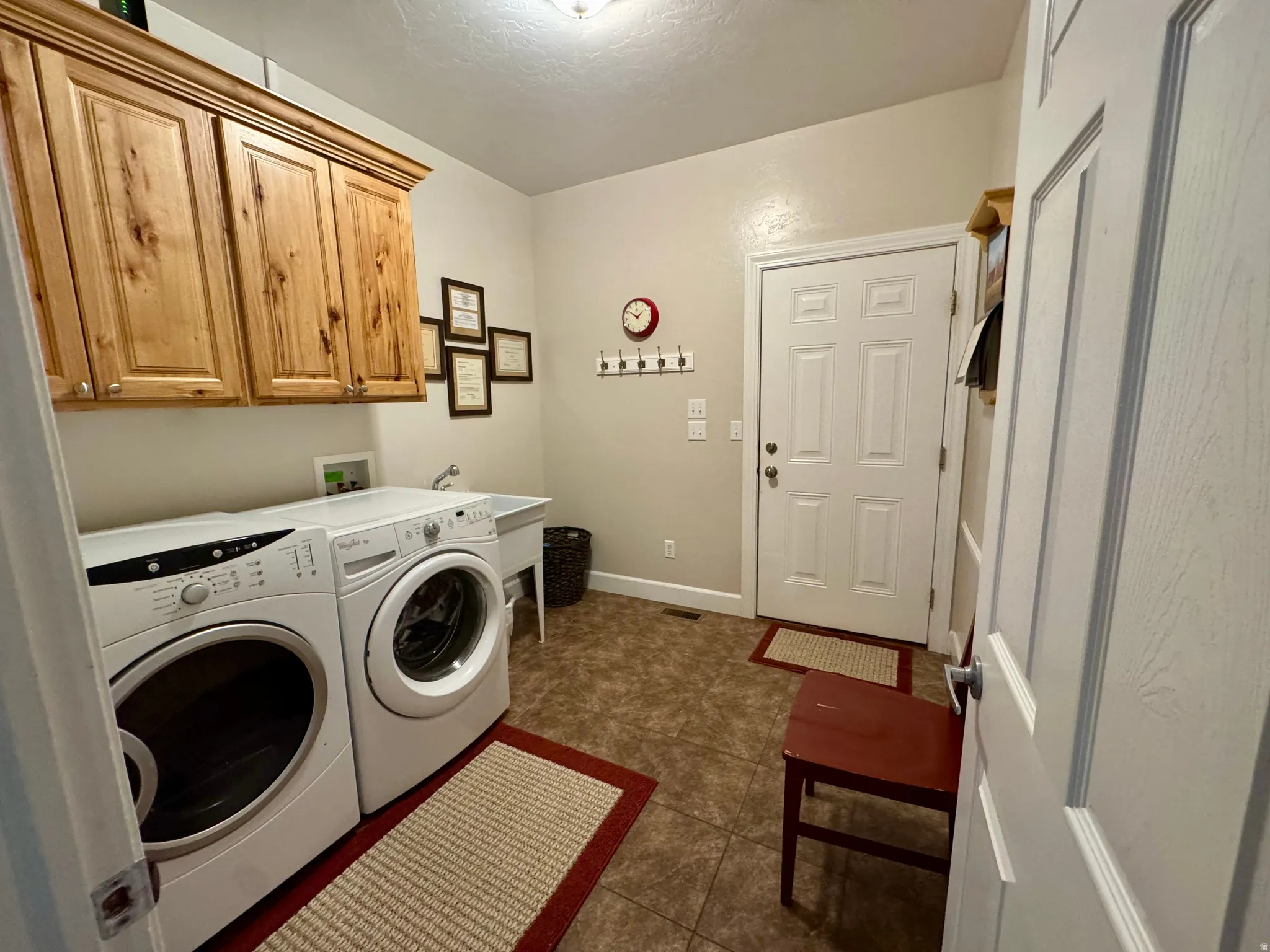 Washroom featuring cabinet space, independent washer and dryer, and dark tile patterned flooring