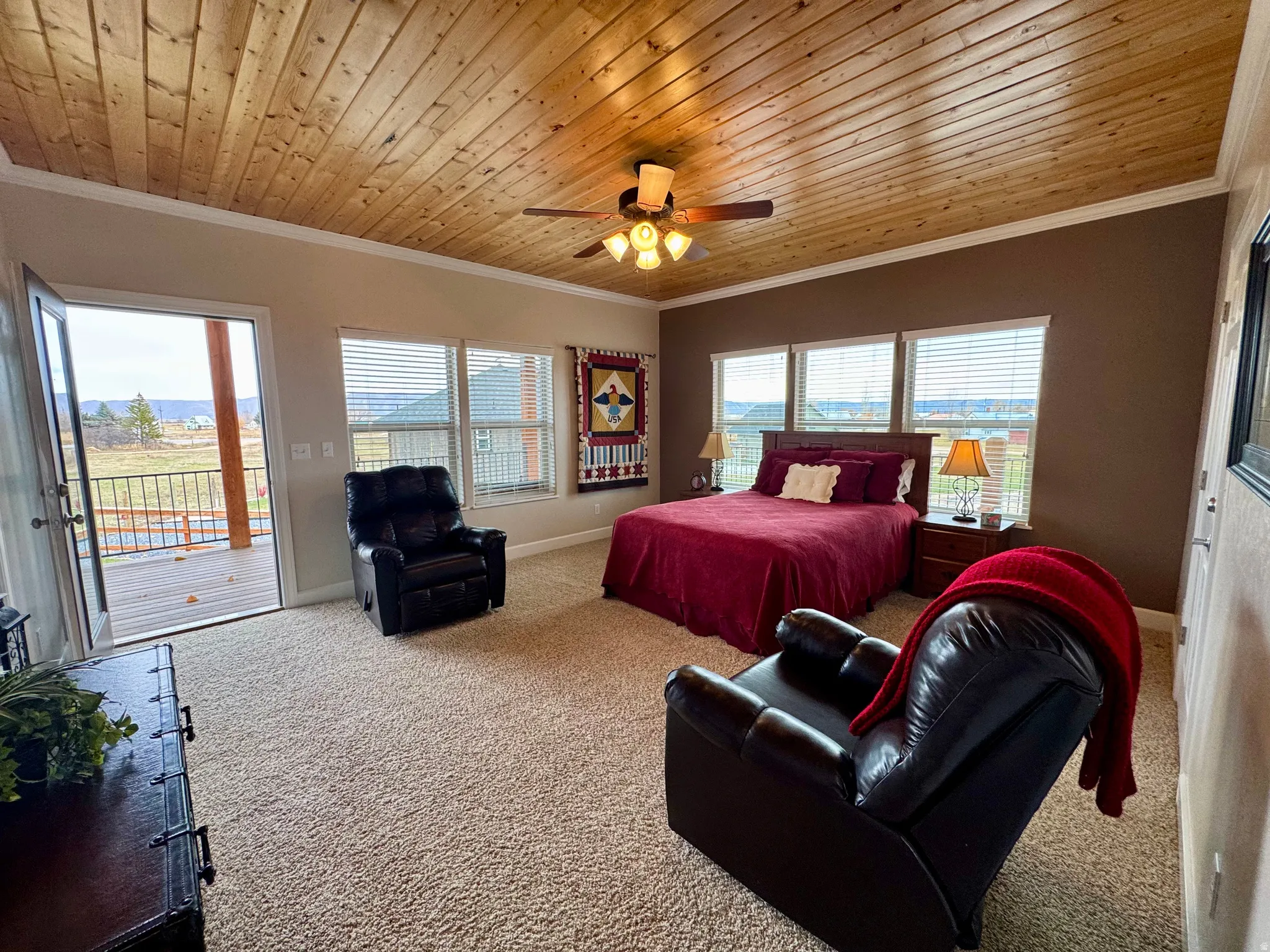 Primary bedroom with crown molding, wooden ceiling, access to exterior, multiple windows, and ceiling fan