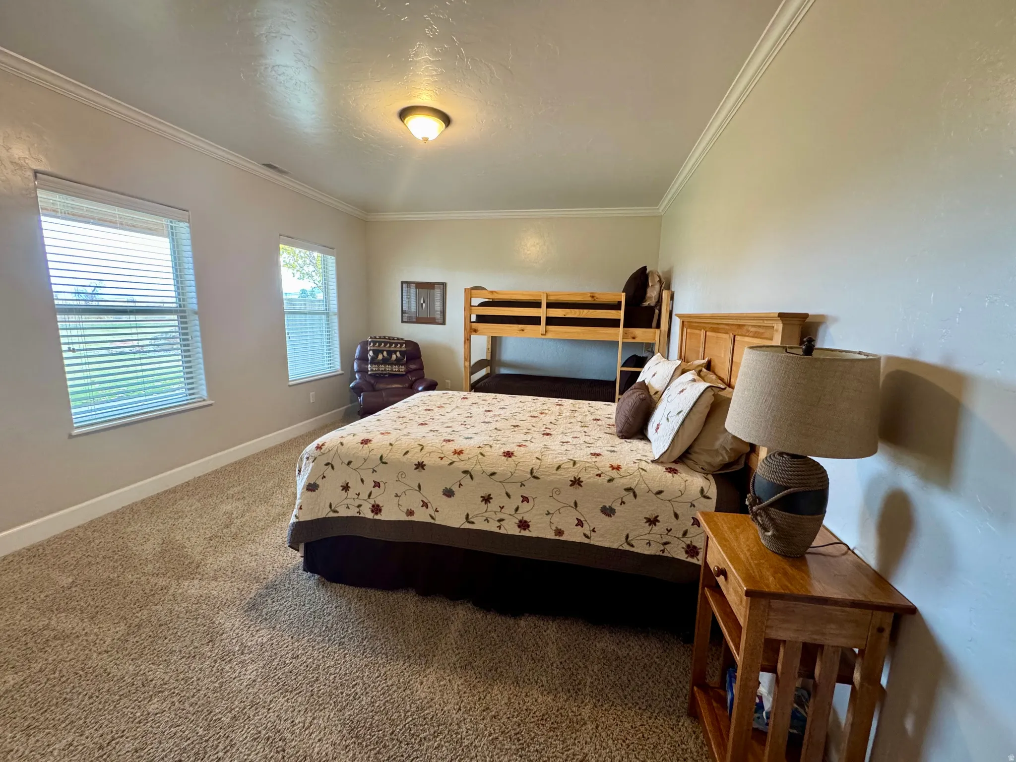 Bedroom with crown molding, carpet floors, and a textured ceiling