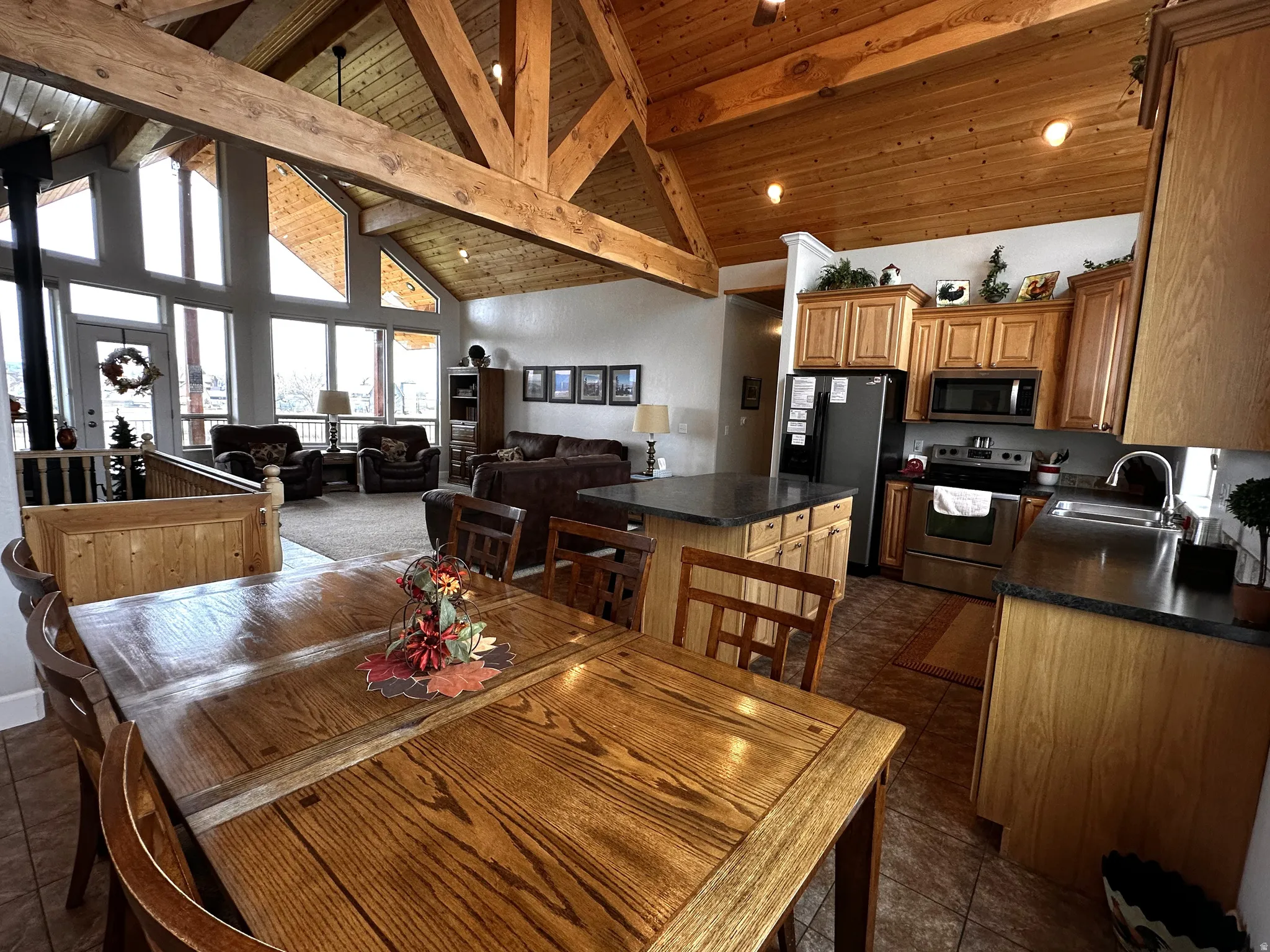 Dining room featuring high vaulted ceiling, a wood ceiling with exposed beams, plenty of natural light, and dark tile patterned flooring