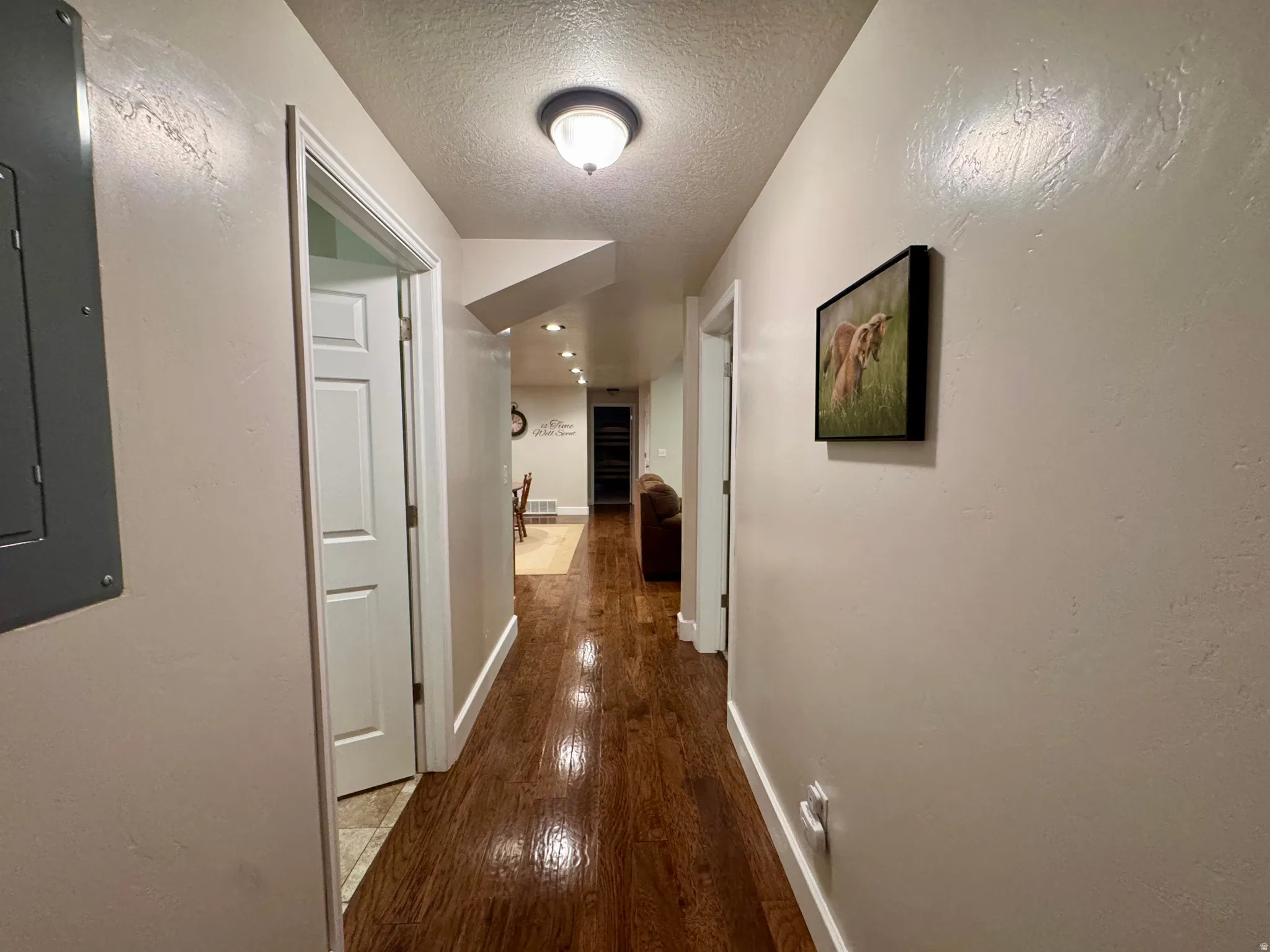 Corridor featuring a textured ceiling, dark wood finished floors, electric panel, and recessed lighting