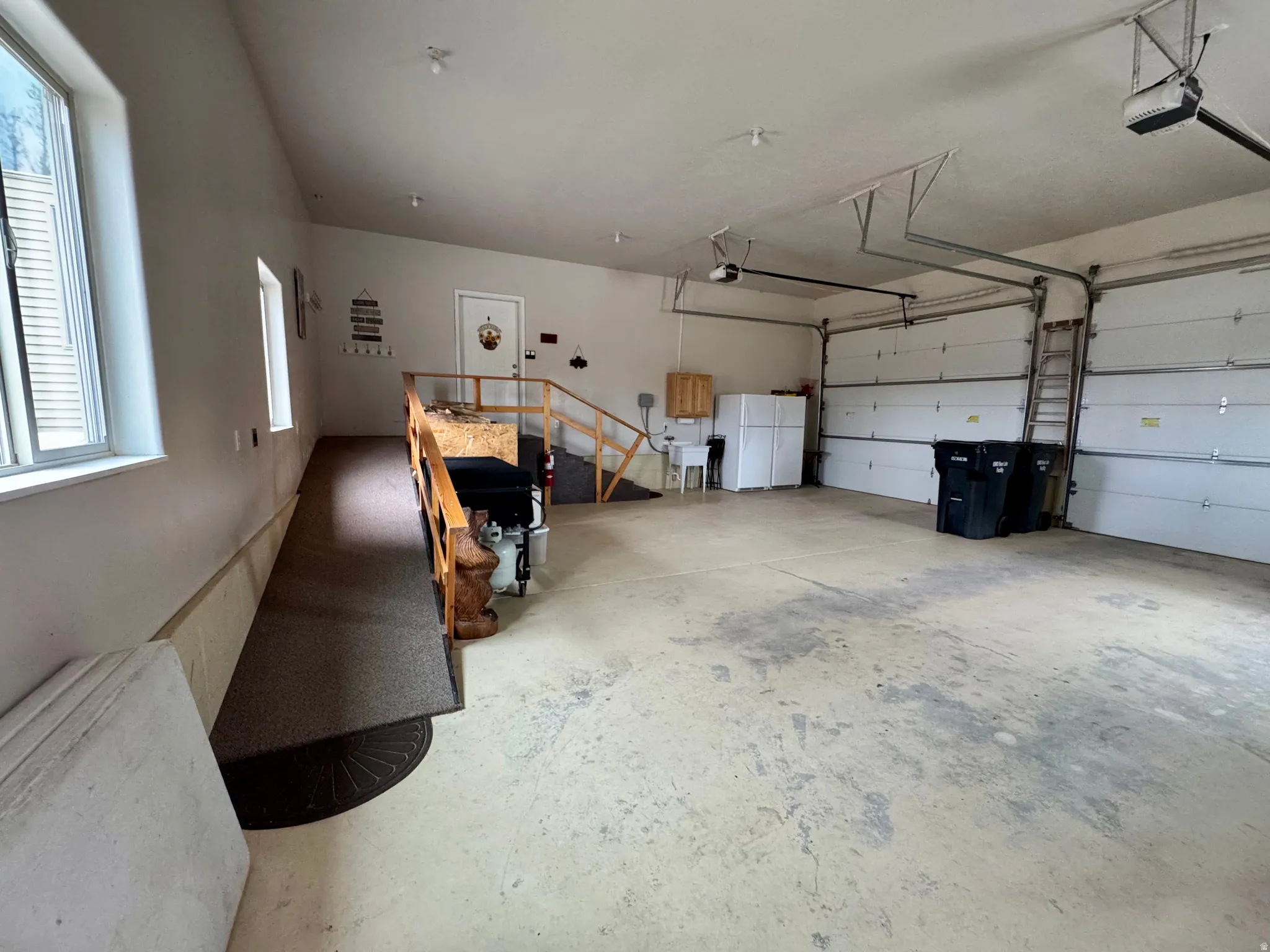 Garage featuring freestanding refrigerator and a garage door opener