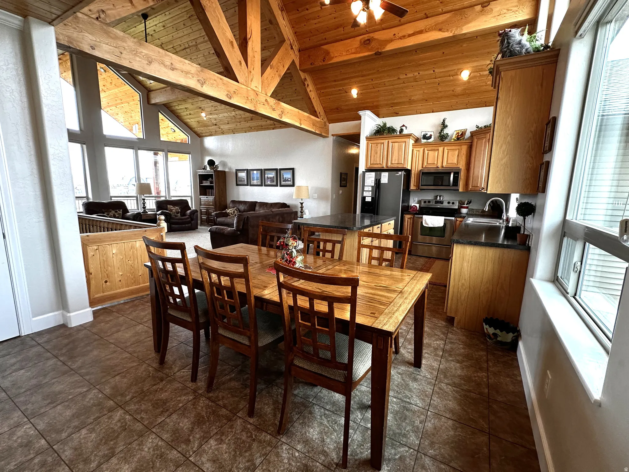 Dining room featuring plenty of natural light, high vaulted ceiling, and a wooden ceiling with exposed beams