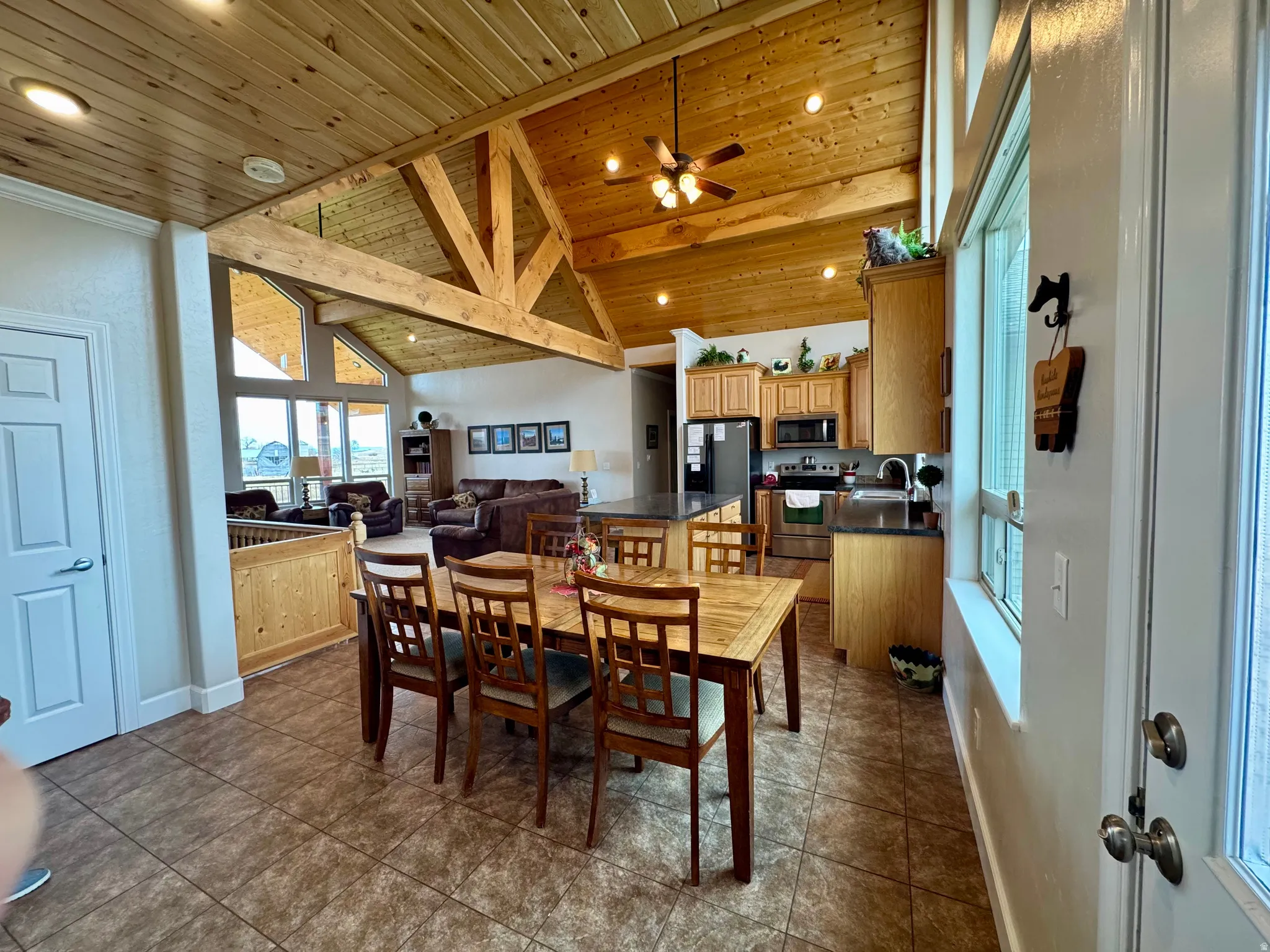Dining space featuring a wooden ceiling with exposed beams, high vaulted ceiling, recessed lighting, dark tile patterned flooring, and ceiling fan