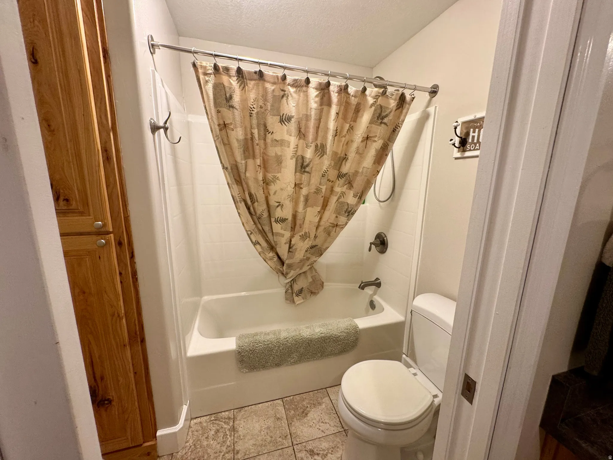 Bathroom featuring shower / bathtub combination with curtain, a textured ceiling, and tile patterned flooring